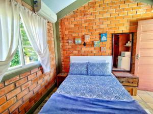 a bedroom with a blue bed in a brick wall at Suíte Rústica in Florianópolis