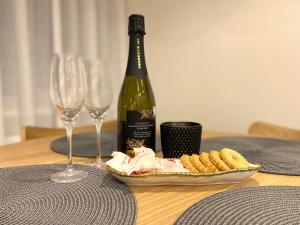 a bottle of wine and a plate of food and wine glasses at Cozy Home Jekaba Apartment, old town, self check-in in Riga