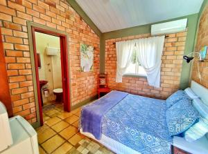 1 dormitorio con 1 cama azul en una pared de ladrillo en Suíte Rústica en Florianópolis