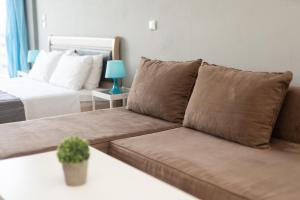 a living room with a brown couch and a bed at Glykanisos Mini Suites in N&eacute;a P&eacute;ramos