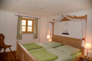 a bedroom with a bed with green sheets and a window at Mühle zu Waching in Brannenburg