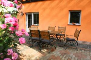 a table and chairs sitting next to a building with pink roses at Ferienhaus Spreewald Linde​ in Belten