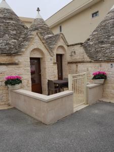 uma casa com uma varanda com uma mesa e flores em TRULLO GIUVICA em Locorotondo