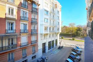 an apartment building with cars parked in a parking lot at Genteel Home Retiro in Madrid
