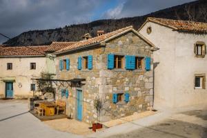 un viejo edificio de piedra con persianas azules. en Mountain Lodge Istria, Tiny house en Roč