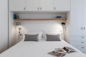 Una cama blanca con dos almohadas y una revista. en Contempora Apartments - Casale 3, en Milán
