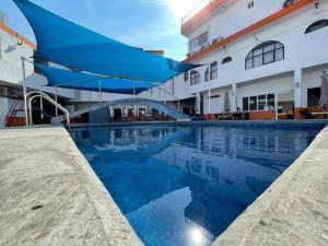 a swimming pool with a blue umbrella next to a building at Hotel Moreno in Ciudad Valles