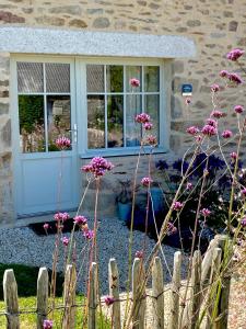 a house with a blue door and pink flowers at La Grange Neuve in Plougonvelin
