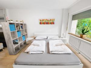 a white bedroom with two beds and a window at Little Black Forest Garden in Pforzheim