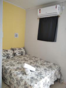 um quarto com uma cama e ar condicionado na parede em Hospedagem ensolarada em Japaratinga