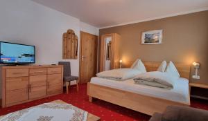 a bedroom with a bed and a flat screen tv at Pension Schweizerhof in Waidring