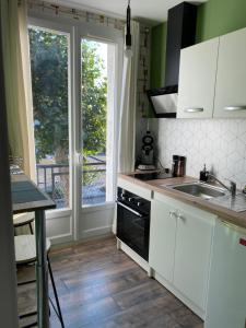 a kitchen with white cabinets and a sink and a window at L’havrais détente in Le Havre