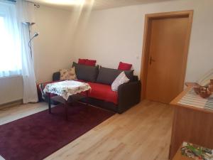 sala de estar con sofá rojo y mesa en Ferienwohnung im Blumengarten, en Angermünde