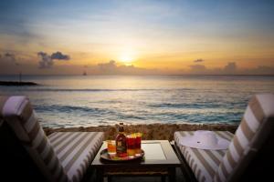 uma mesa e cadeiras na praia com o pôr do sol em The Club Barbados - All Inclusive - Adults Only em Saint James