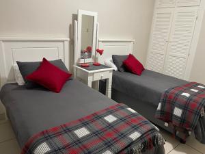 two beds with red pillows in a room at 3 Eden Sands in Kingsborough