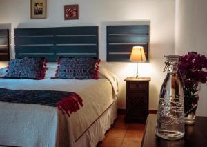 a bedroom with a bed with a blue headboard and a table at Hotel la Galería in Antigua Guatemala