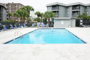 une grande piscine avec des chaises et un bâtiment dans l'établissement Cherry Grove Retreat & Sea Cabin, à Myrtle Beach