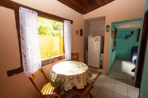 eine Küche mit einem Tisch, einem Fenster und einem Kühlschrank in der Unterkunft Casa Maresias a 950m a pé da praia c churrasqueira in Maresias