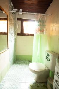 ein grünes Badezimmer mit Toilette und Fenster in der Unterkunft Casa Maresias a 950m a pé da praia c churrasqueira in Maresias + 22 Fotos