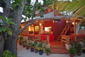 un restaurante con mesas y sillas rojas y un árbol en Stingray Beach Inn en Maafushi