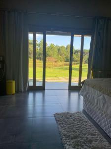 a bedroom with a bed and a view of a field at Chalé dos Pássaros in Gramado