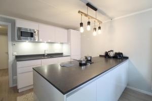 a kitchen with white cabinets and a black counter top at RMG Roses Apartments in Bad Kleinkirchheim