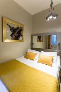 a bedroom with a large bed with yellow pillows at Pratic Hotel in Paris