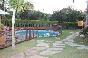 ein Swimmingpool in einem Garten mit Zaun in der Unterkunft San Diego Suítes Hotel Quadrado in Santa Bárbara