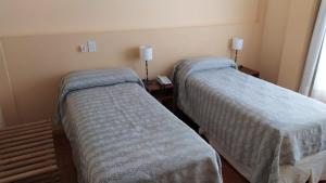 a room with two beds and a table with lamps at LOWCOST MADRYN in Puerto Madryn