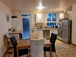 una cucina con tavolo, sedie e frigorifero di Appartements avec piscine a Durtal