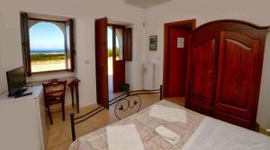 a bedroom with a bed and a desk and a window at La Piana degli Ulivi in Ostuni