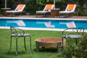 dos sillas y una mesa en el césped junto a una piscina en Alacati LuCe Design Hotel - Special Category, en Alacati