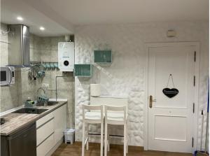 a kitchen with two white chairs and a white door at Loft Ben A Ocaz in Benaocaz