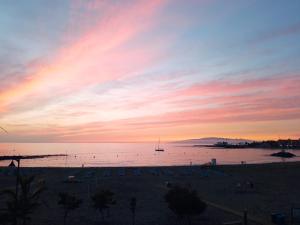 un tramonto su una spiaggia con una barca in acqua di Estudio Helen and Peter a Los Cristianos Altre 2 foto