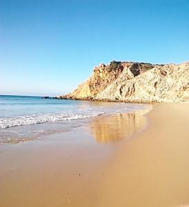 a sandy beach with the ocean and a mountain at Hotel Burgau Turismo de Natureza in Burgau