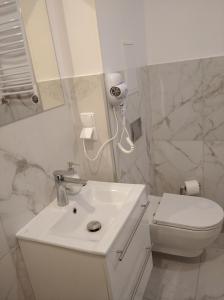 a white bathroom with a sink and a toilet at Familijny in Toruń