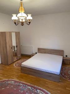 een slaapkamer met een bed en een kroonluchter bij Casa Sia in Tîrgu Ocna