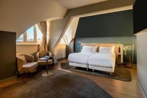 a living room with a large bed and a large window at NH Collection Salzburg City in Salzburg