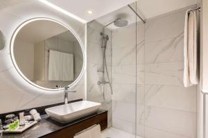 a bathroom with a shower, sink, and mirror at NH Collection Salzburg City in Salzburg