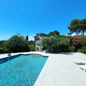 einen Pool mit zwei Stühlen und ein Haus in der Unterkunft Villa La Carpenée in Roquefort-les-Pins