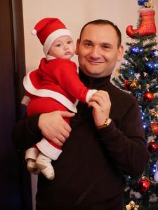 un hombre sosteniendo un bebé vestido con un traje de Navidad en Villa GabLile en Mestia