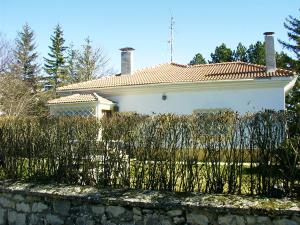 een wit huis met een hek ervoor bij El Uncar in Castrejón de la Peña