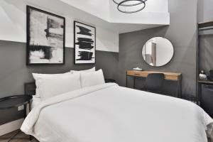 une chambre avec un lit blanc et un miroir dans l'établissement Hygie Boutique Hotel, à Montréal