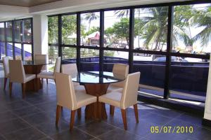 une salle à manger avec une table, des chaises et des fenêtres dans l'établissement Flat Praia do Cabo Branco - Casados para sempre!, à João Pessoa