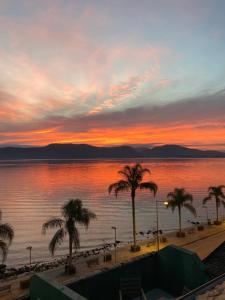 puesta de sol sobre una playa con palmeras y agua en Hotel Solar da Beira en São Francisco do Sul