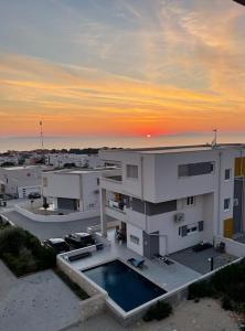 a building with a swimming pool in front of a sunset at Seastar Luxury apt with PRIVATE POOL and sea view in Novalja