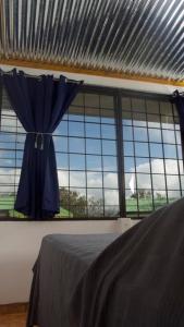 ein Schlafzimmer mit einem Fenster mit einem blauen Regenschirm in der Unterkunft Basecamp Arenal in Tronadora