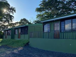 a green building with windows and a fence at Basecamp Arenal in Tronadora