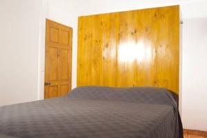 Basecamp Arenal في Tronadora: غرفة نوم بسرير وجدار خشبي