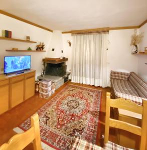 uma sala de estar com um sofá e uma televisão em Trilocale accogliente con camino a pochi minuti da Madonna di Campiglio em Spiazzo